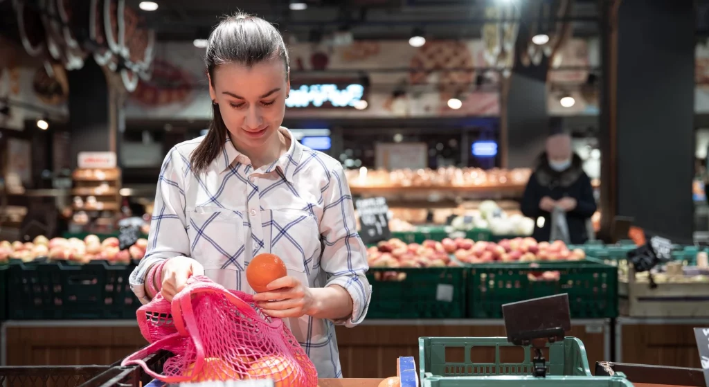 woman picking fruits up at trader joes