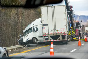 White semi-truck jackknifed on the highway with debris and orange traffic cones nearby
