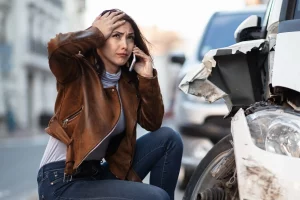 Frustrated woman calling for road assistance after a Houston car accident.